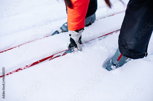 Man is skiing. Close-up of legs in gray ski boots on skis, man bent down and picked up ski lying on snow. 