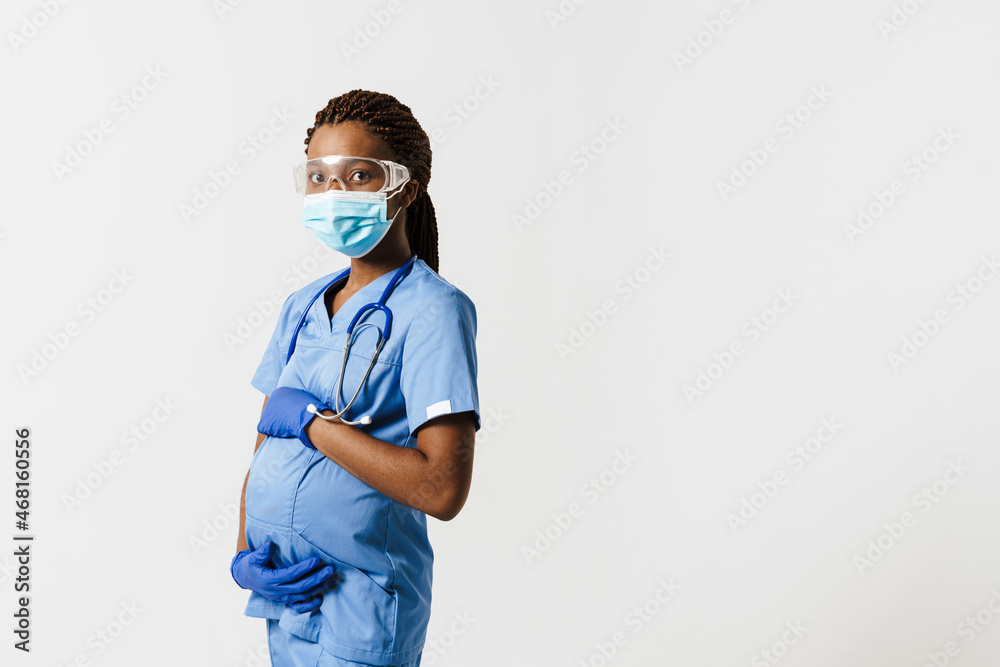 Black pregnant doctor wearing face mask posing with stethoscope Black pregnant doctor wearing face mask posing with stethoscope