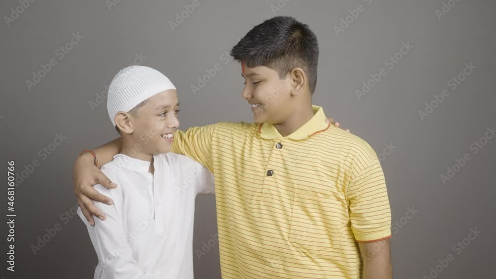 Happy Hindu Muslim kids showing unity by holding hands together by looking at camera on gray background - concept of diversity, bonding and multiethnic friendship. Happy Hindu Muslim kids showing unity by holding hands together by looking at camera on gray background - concept of diversity, bonding and multiethnic friendship.