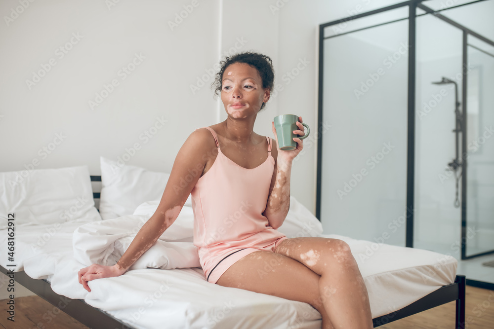 A young woman enjoying her morning herbal tea and looking contented A young woman enjoying her morning herbal tea and looking contented