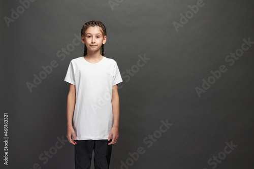 Kid girl wearing white t-shirt with space for your logo or design in studio over gray background