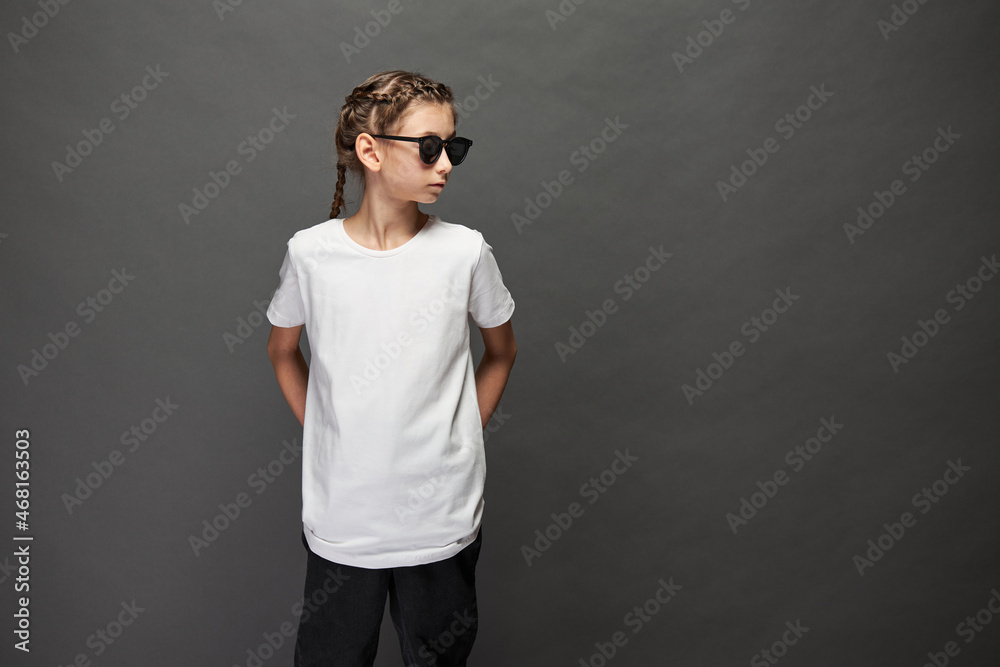Kid girl wearing white t-shirt with space for your logo or design in studio over gray background Kid girl wearing white t-shirt with space for your logo or design in studio over gray background