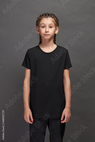 Kid girl wearing black t-shirt with space for your logo or design in studio over gray background