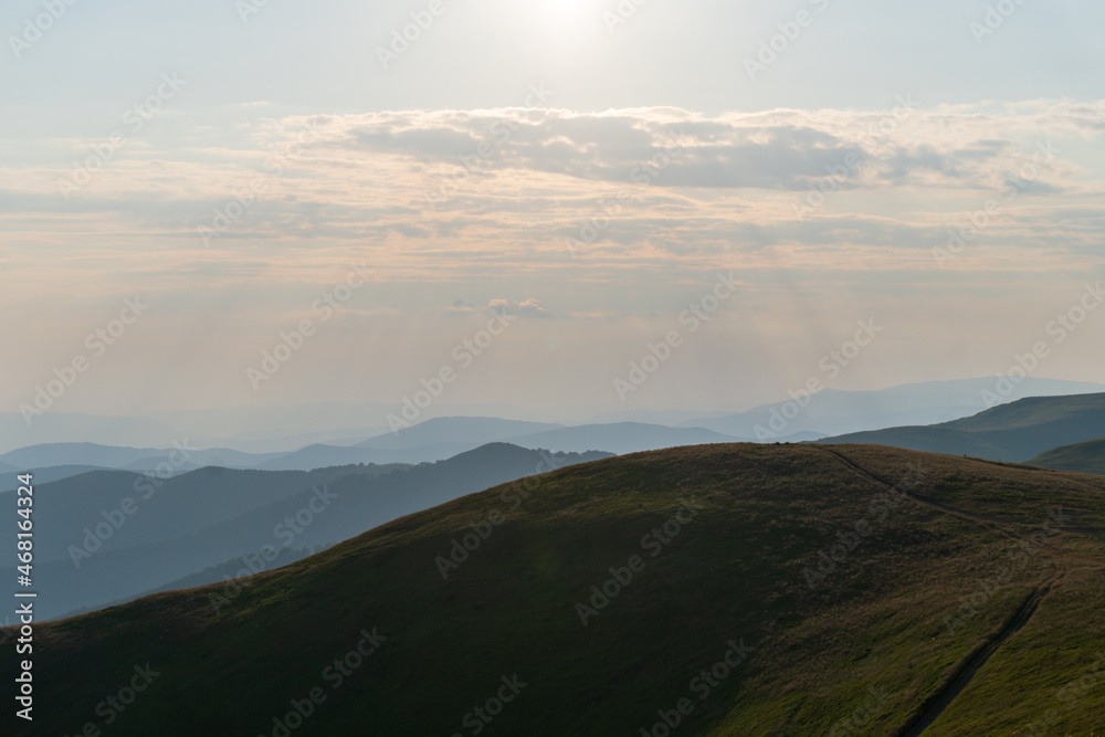 Picturesque sunset. A calm evening fell on mountain ranges overgrown with green forest. The sky is painted with the warm colors of the setting sun. Nature Ukraine, Carpathian Mountains