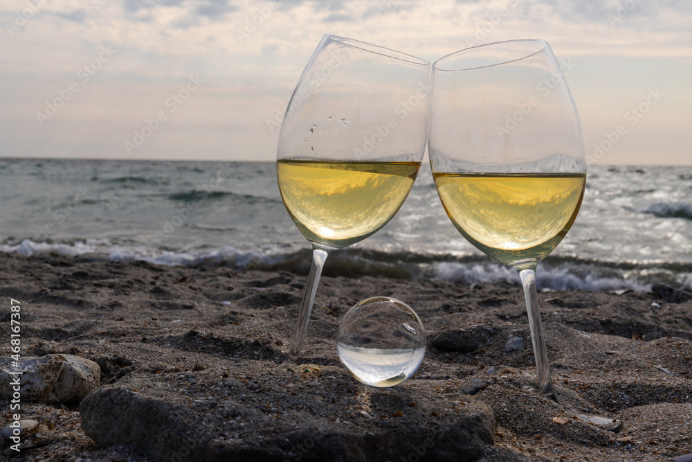 Romantic glass of white wine, on the sea beach. Wine tasting and relaxation at the resort Romantic glass of white wine, on the sea beach. Wine tasting and relaxation at the resort