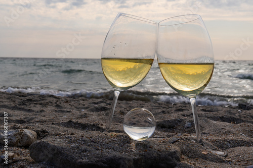 Romantic glass of white wine, on the sea beach. Wine tasting and relaxation at the resort