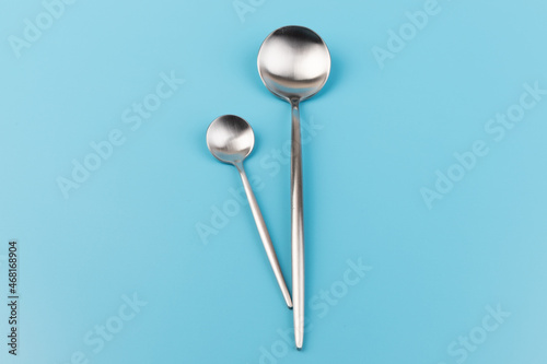 Clean empty  big table spoon and small spoons on blue background, top view. Space for text