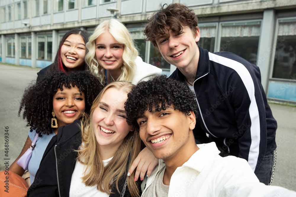 Portrait of smiling male and female friends against building
