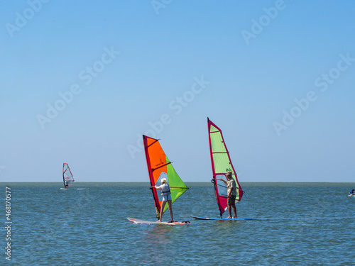 The instructor teaches the girl to control windsurfing. A calm sea where you can do water sports on a sailing board. Great time at sea with windsurfing and surfing. Russia, Yeysk, August 5, 2020 photo