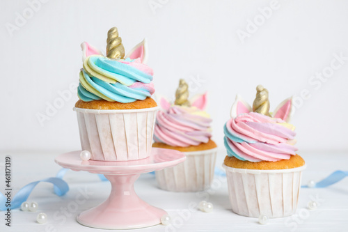 Cute sweet unicorn cupcakes on white table