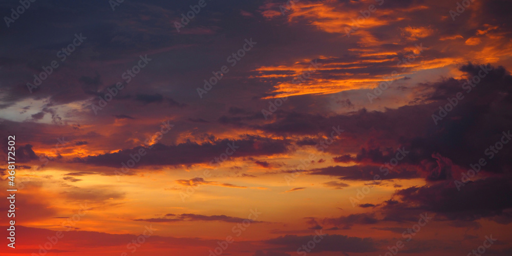 Fototapeta premium Fiery orange-red sunset sky. Dramatic sunset sky with clouds. A real majestic sunset sky background with colorful clouds. Beautiful sky