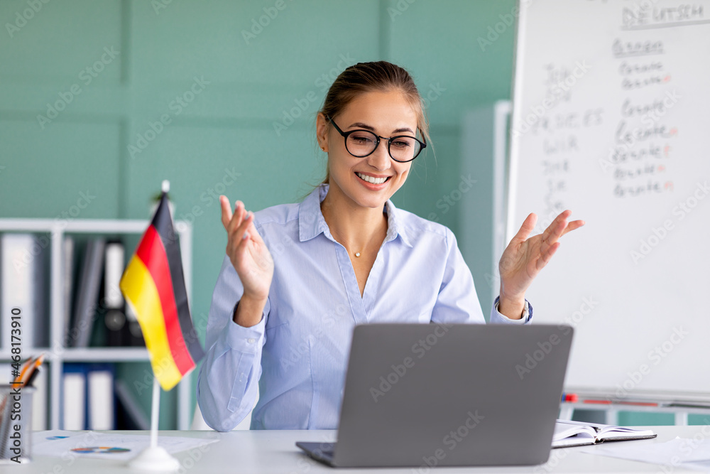 E-learning with teacher, social distancing. Happy female tutor giving German language lesson online on laptop - obrazy, fototapety, plakaty 