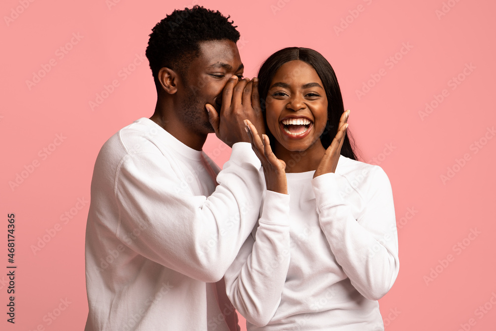 Obraz premium Handsome black guy whispering his girlfriend something exciting