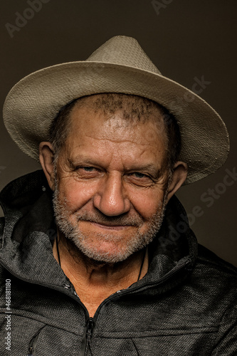 Studio portrait of an elderly caucasian man with gray stubble in a hat