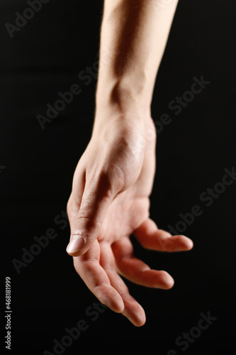 an open hand on a black background hangs down