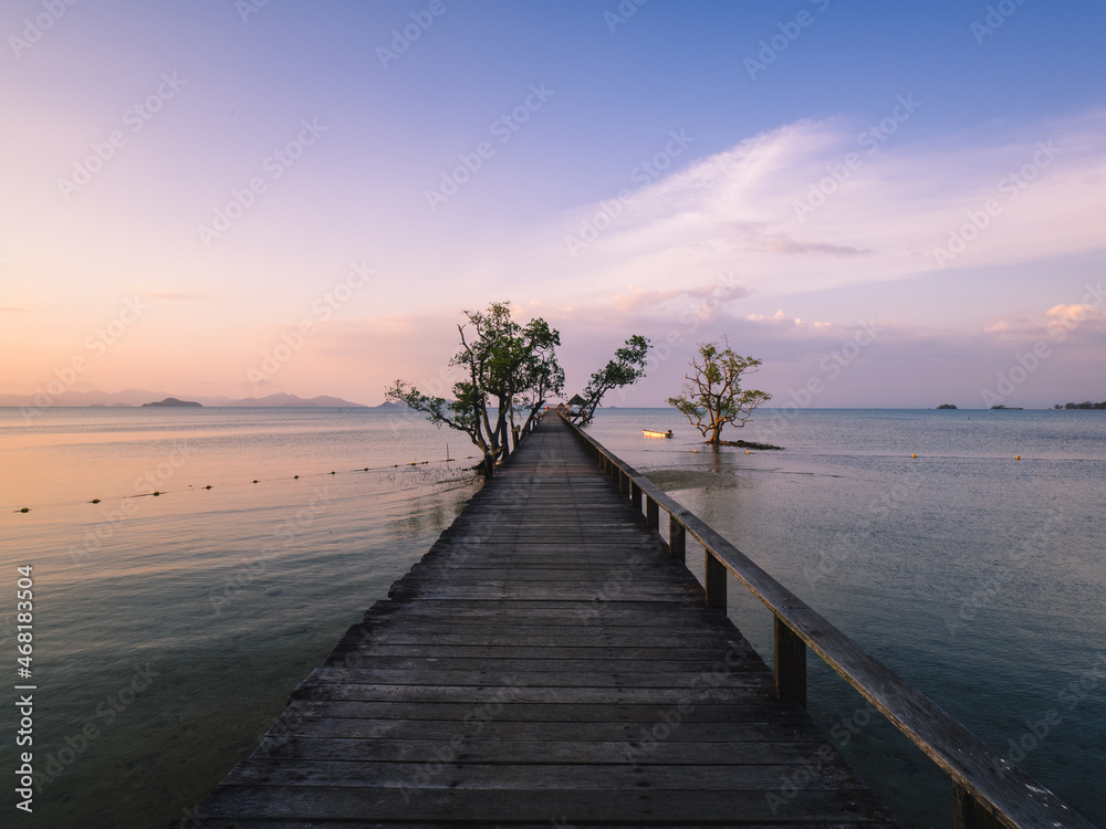 Scenic view of long straight wooden pier over peaceful water in evening orange sky before sunset. Koh Mak Island, Trat Province, Thailand. - obrazy, fototapety, plakaty 