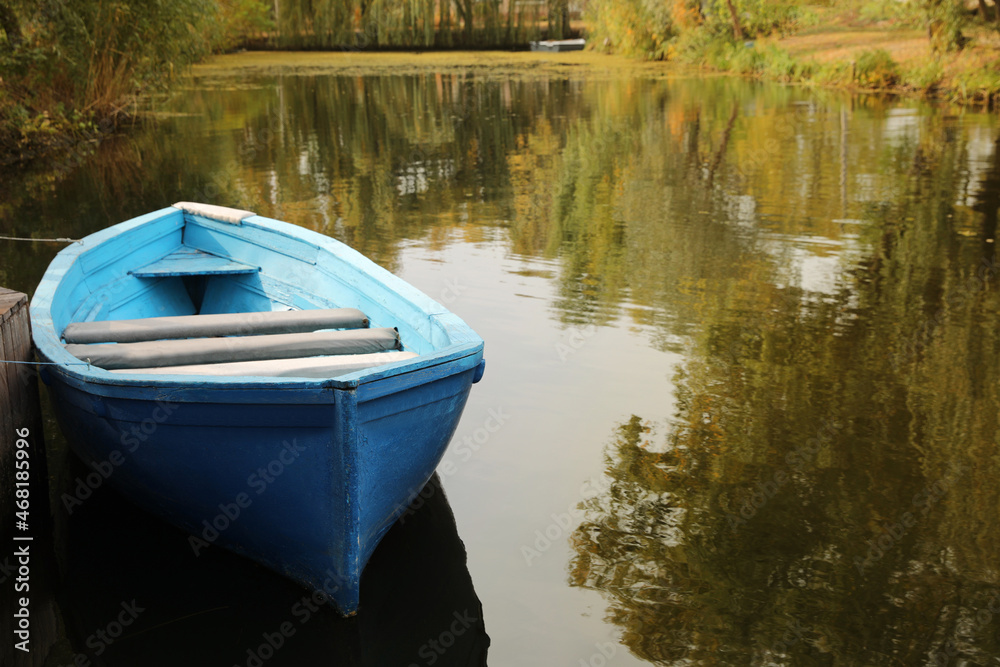 Fototapeta premium Light blue wooden boat on lake, space for text