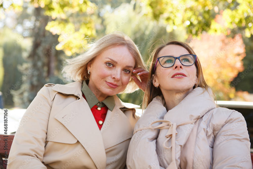 Two mature lovely female friend enjoying warm autumn day in the park together Two mature lovely female friend enjoying warm autumn day in the park together