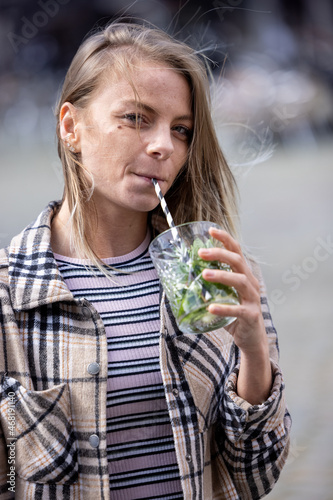 Attractive young caucasian woman or twentysomething girl drinking mojito with straw in city center during happy hour. High quality photo photo