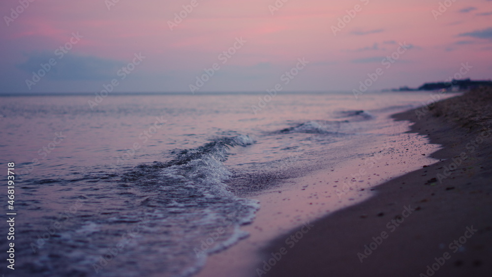 Purple sky reflecting at sea water surface at cold evening sunset. Calm waves 