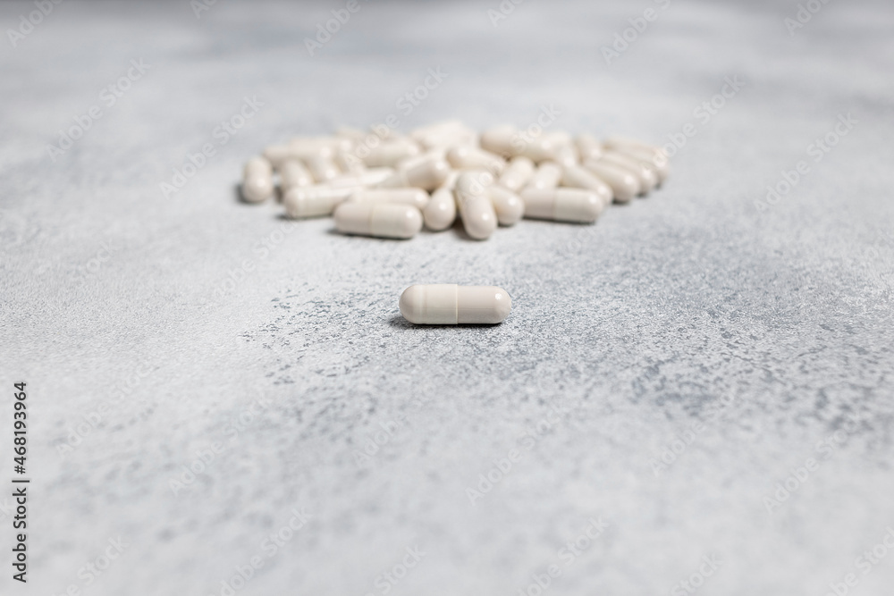 one white capsule of cure on background of bunch of pills. medical healthcare concept of virus pandemic protection. coronavirus 2019-nCoV outbreak. prevention of infection, pneumonia one white capsule of cure on background of bunch of pills. medical healthcare concept of virus pandemic protection. coronavirus 2019-nCoV outbreak. prevention of infection, pneumonia