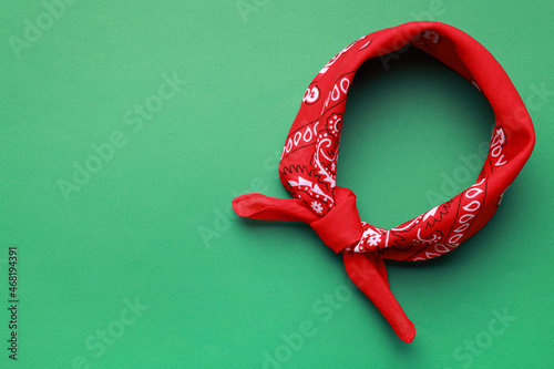 Tied red bandana with paisley pattern on light green background, top view. Space for text