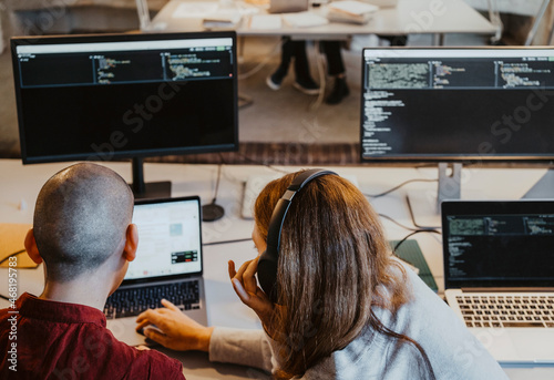 High angle view of female and male hackers coding over laptop in office photo
