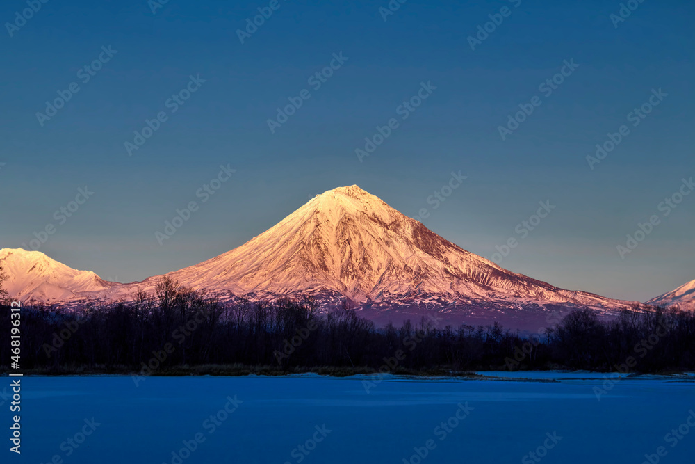 Snow-capped mountain in the evening light of the setting sun. Hill, winter landscape. Snow-capped mountain in the evening light of the setting sun. Hill, winter landscape.