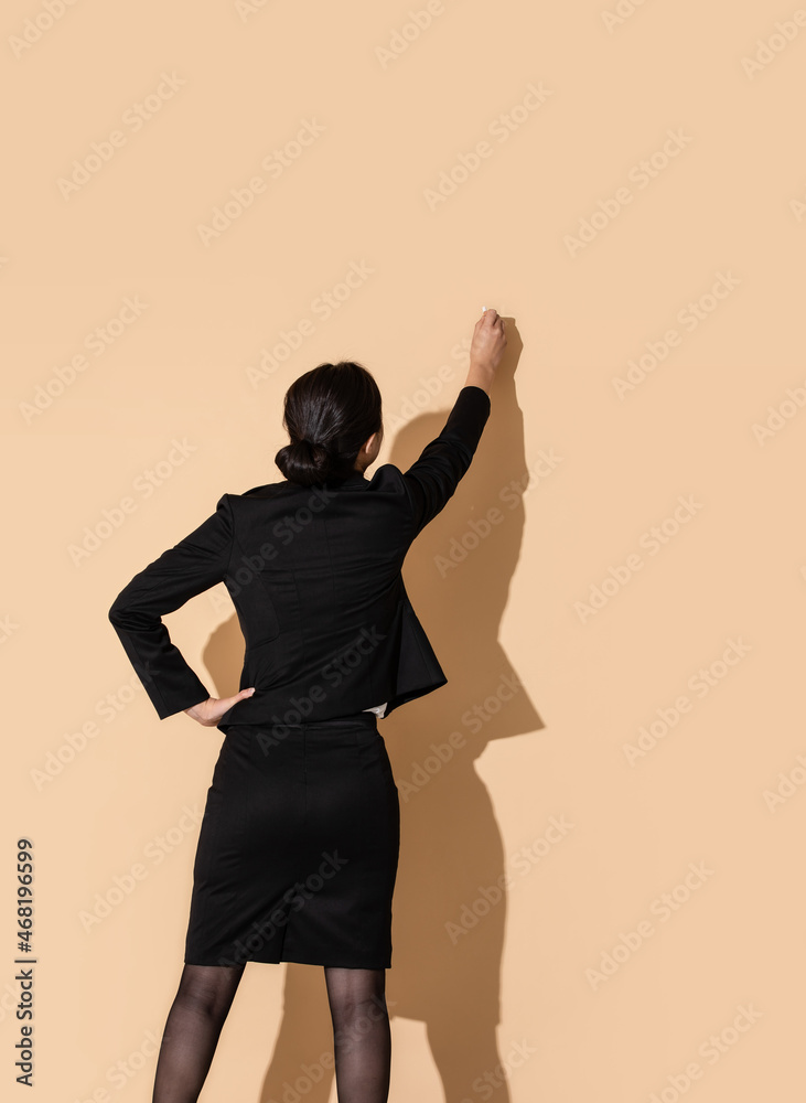 A woman is holding a chalk and writing on a blackboard A woman is holding a chalk and writing on a blackboard