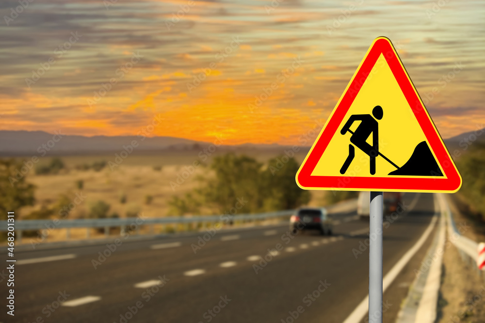 Traffic sign Road Works near highway at sunset Traffic sign Road Works near highway at sunset