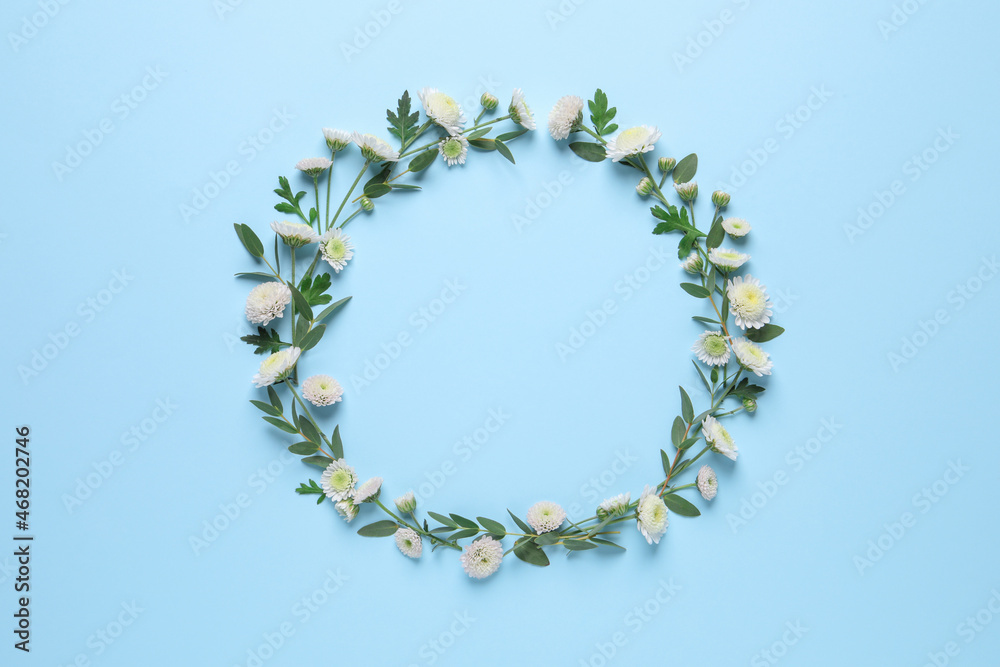 Wreath made of beautiful flowers and green leaves on light blue background, flat lay. Space for text Wreath made of beautiful flowers and green leaves on light blue background, flat lay. Space for text