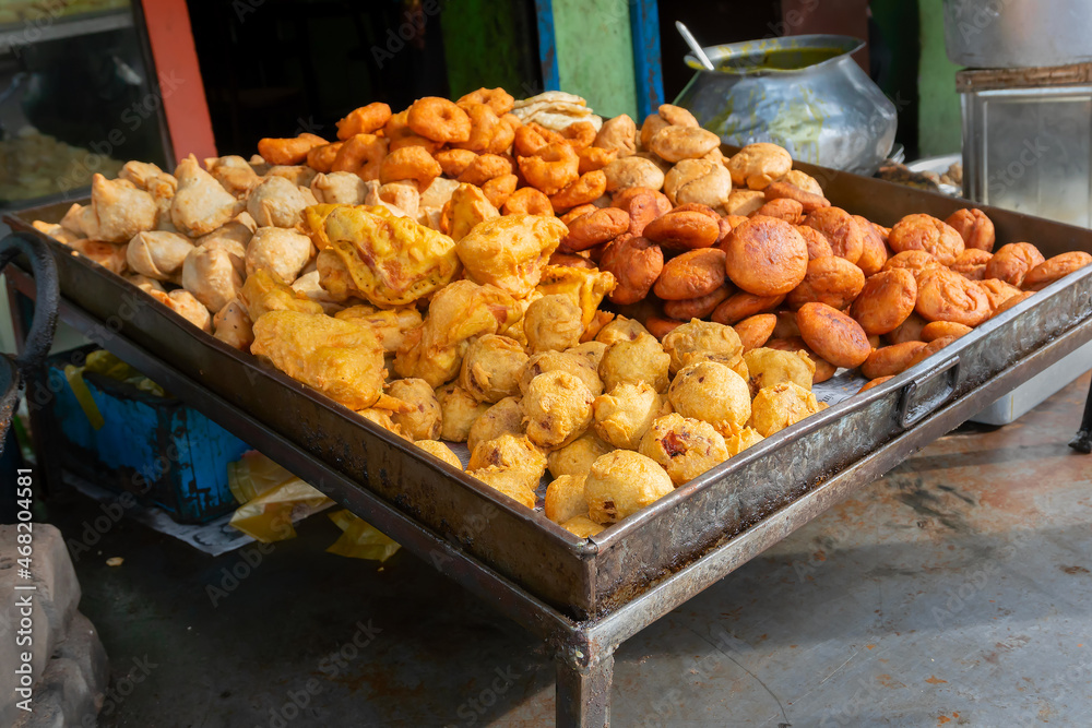 Various fast foods like Piiyaji, gulgula, bara, aloo chop, mangso chop, etc, are being sold by cart puller called thelawalla , are displayed for sale. Image of street foods of Cuttack, Odisha, India.
