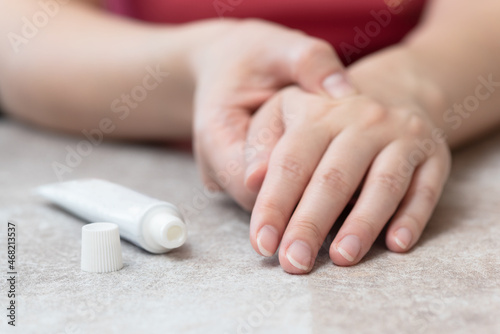 фотографія Woman is applying a pain reliever cream to her hand close up.