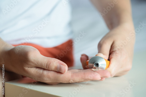 Woman is applying a pain reliever cream to her hand close up.