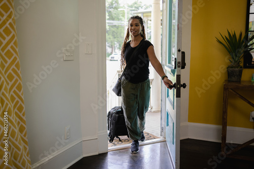 African American Woman with luggage entering house, vacation, urban photo