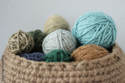 Skeins of colored yarn in a jute basket on a white background