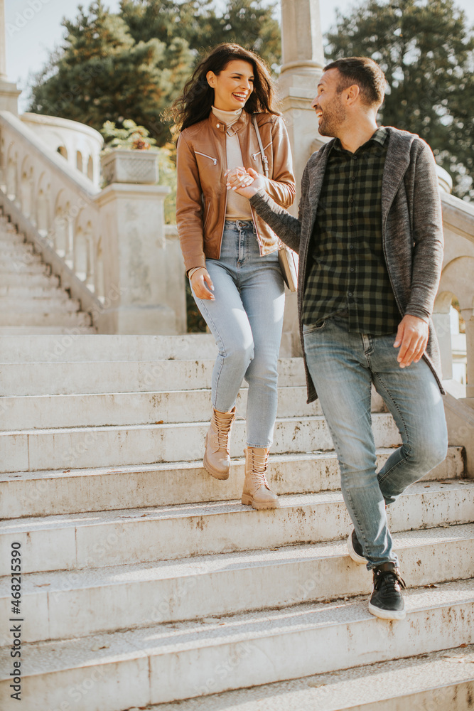 Young couple smiling and talking while strolling down outdoor stairs on autumn day Young couple smiling and talking while strolling down outdoor stairs on autumn day
