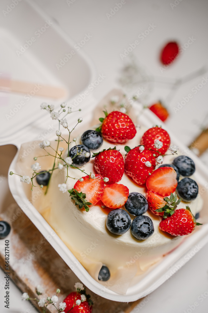 Beautiful white cake decorated with strawberries, blueberries and flowers Beautiful white cake decorated with strawberries, blueberries and flowers