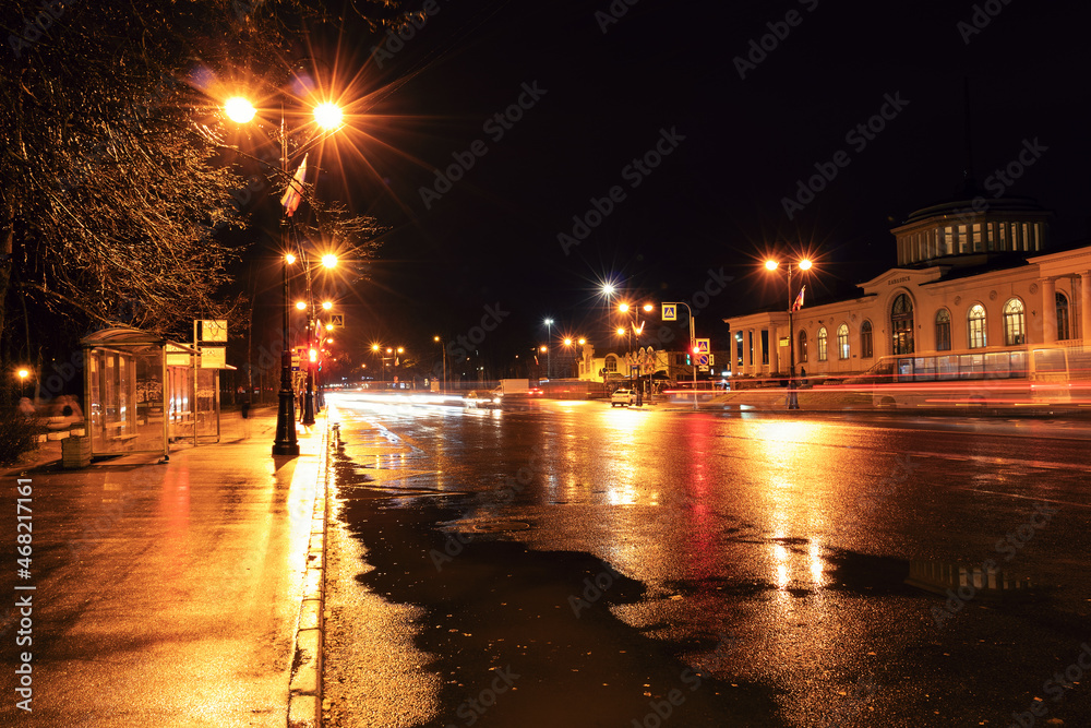 Night city street with bus stop, pedestrian crossing, street light and wet asphalt