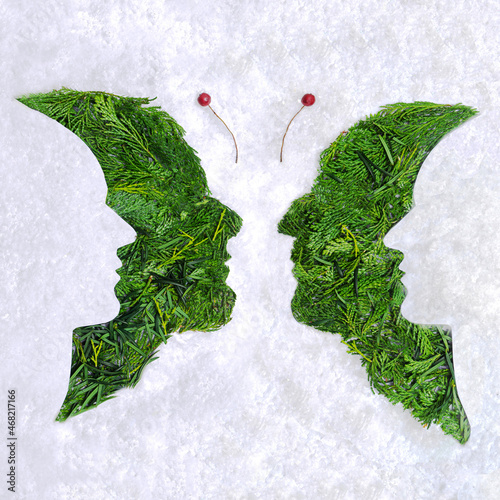 Psychology and optical illusion abstract concept four faces butterfly image. Flat lay arrangement of different shapes and color of arborvitae leaves against snowy white background.