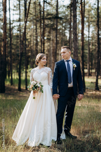 the bride and groom are walking in a pine forest © omelnickiy