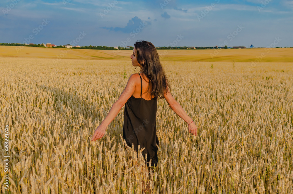 Beautiful woman with black hair on a wheat field. Dreamy look. View from the back Beautiful woman with black hair on a wheat field. Dreamy look. View from the back