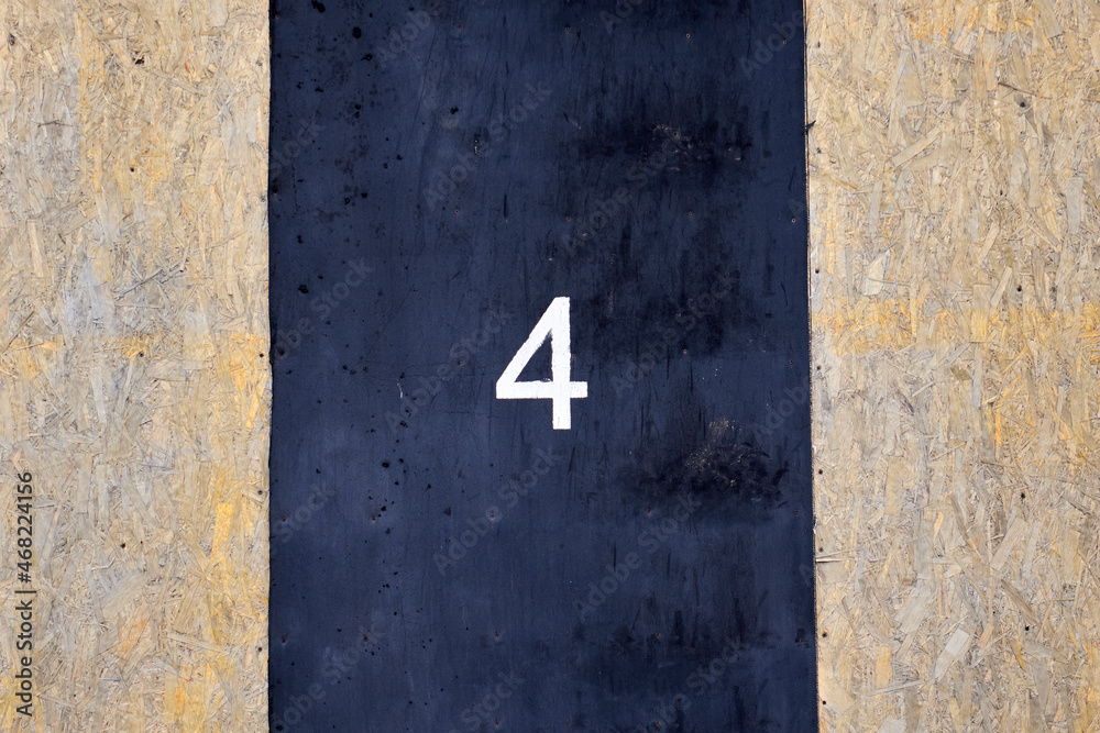Number 4 painted with white paint on a black rubber surface Number 4 painted with white paint on a black rubber surface