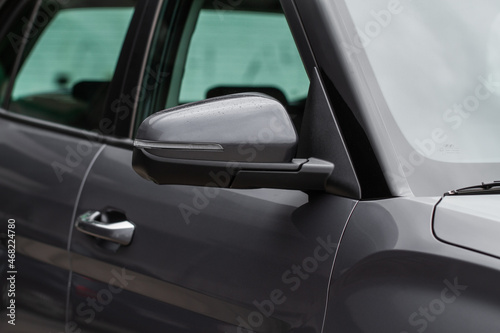 Close up front view of car side mirror. Front rear view mirror on the car window. Car exterior details. Gray car mirror. © Roman