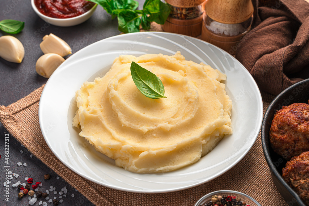 Mashed potatoes in a white plate with basil close-up.