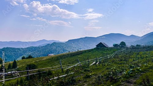 Panoramic view of idyllic Carpathian mountain scenery with authentic house. Traditional mountain house on green field