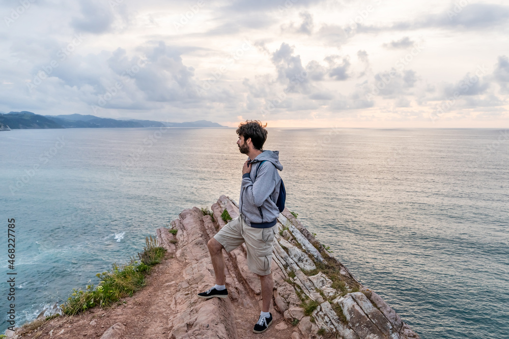 Horizontal view of adventurous traveler man sightseeing in Zumaia cliffs. Horizontal panoramic view of man traveling in vasque country. People and travel destination in Spain