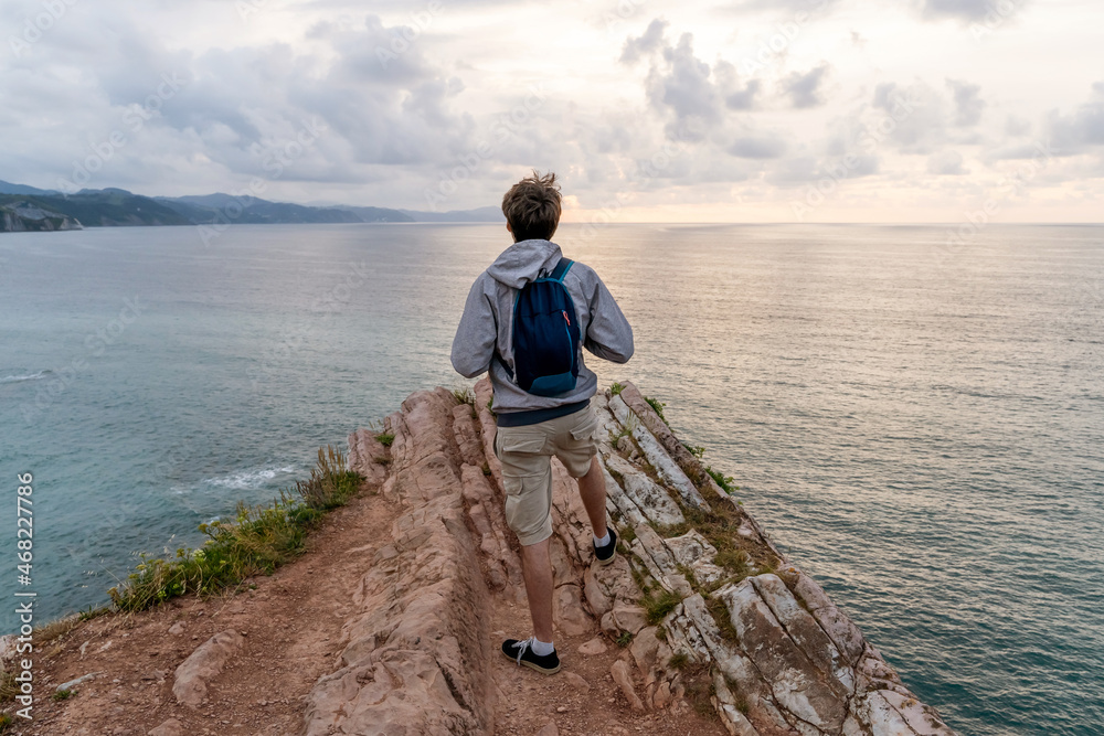Horizontal view of unrecognizable traveler man sightseeing in Zumaia cliffs. Horizontal panoramic view of man traveling in vasque country. People and travel destination in Spain Horizontal view of unrecognizable traveler man sightseeing in Zumaia cliffs. Horizontal panoramic view of man traveling in vasque country. People and travel destination in Spain