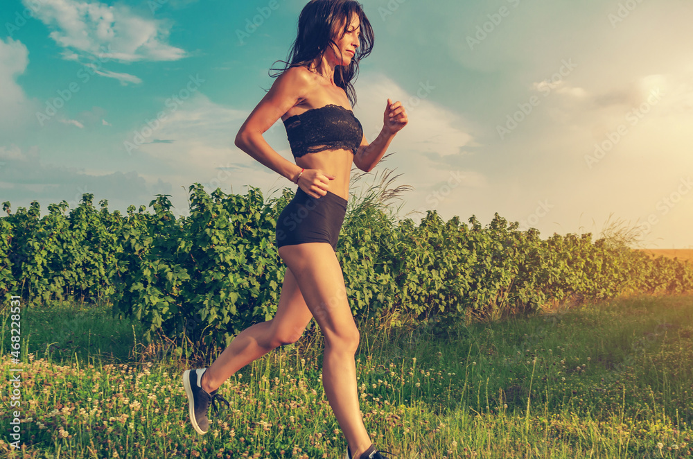 Beautiful woman running across the field. Short black shorts, top Beautiful woman running across the field. Short black shorts, top