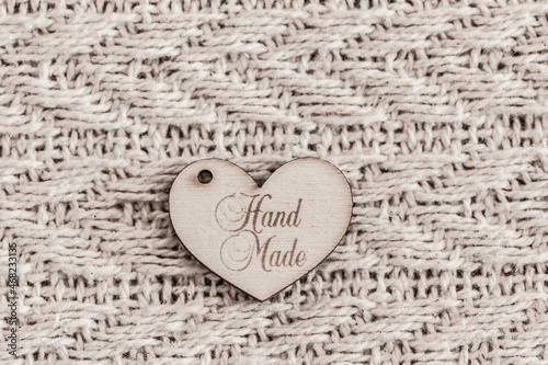 Wooden label  sign     handmade     in shape of heart on knitted textured background. Mock up  top view